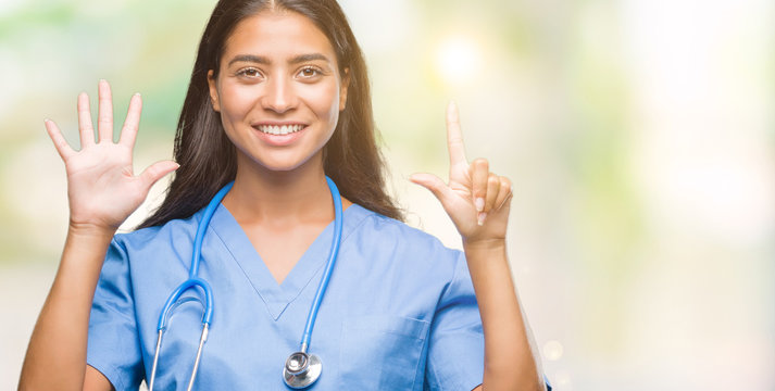 Young arab doctor surgeon woman over isolated background showing and pointing up with fingers number seven while smiling confident and happy.