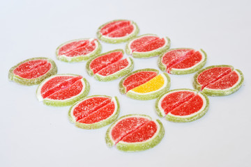 The marmalade slices in the form of watermelon and lime lie on a white surface. Stand out from the crowd