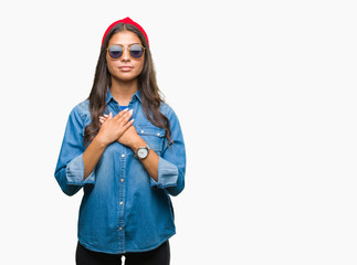 Young beautiful arab woman wearing sunglasses over isolated background smiling with hands on chest with closed eyes and grateful gesture on face. Health concept.