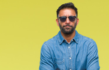 Adult hispanic man wearing sunglasses over isolated background skeptic and nervous, disapproving expression on face with crossed arms. Negative person.