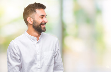 Naklejka premium Adult hispanic man over isolated background looking away to side with smile on face, natural expression. Laughing confident.