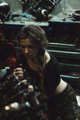 Obraz na płótnie Canvas beautiful girl with long hair in the garage repairing a motorcycle