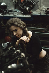 Obraz na płótnie Canvas beautiful girl with long hair in the garage repairing a motorcycle