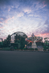 Fototapeta premium Amusement Park with carousel and Rollercoaster, night lights, sunset