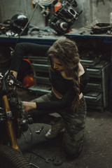 Obraz na płótnie Canvas beautiful girl with long hair in the garage repairing a motorcycle