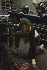Obraz na płótnie Canvas beautiful girl with long hair in the garage repairing a motorcycle