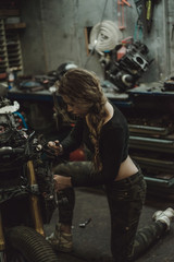 Obraz na płótnie Canvas beautiful girl with long hair in the garage repairing a motorcycle