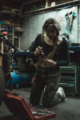 Obraz na płótnie Canvas beautiful girl with long hair in the garage repairing a motorcycle