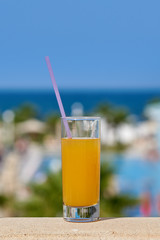Glass of orange juice against the picturesque hotel’s view, illustrating the great family holidays.