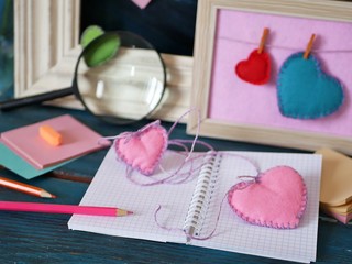 Valentines day, on a blue wooden table, an empty notebook, frames, pencils, felt hearts, bookmarks, preparation concept for a romantic holiday, decorative composition, top view