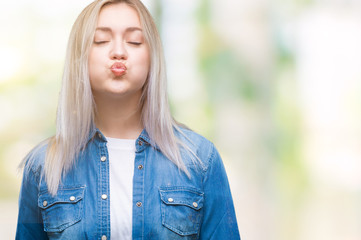 Young blonde woman over isolated background puffing cheeks with funny face. Mouth inflated with air, crazy expression.