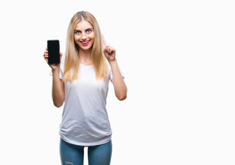 Fototapeta premium Young beautiful blonde woman showing smartphone over isolated background surprised with an idea or question pointing finger with happy face, number one