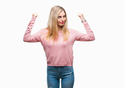 Young beautiful blonde woman wearing pink winter sweater over isolated background showing arms muscles smiling proud. Fitness concept.