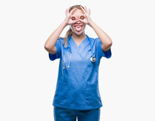 Fototapeta premium Young blonde surgeon doctor woman over isolated background doing ok gesture like binoculars sticking tongue out, eyes looking through fingers. Crazy expression.
