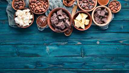 Chocolate, cocoa and cocoa beans on a blue wooden background. Top view. Free copy space.