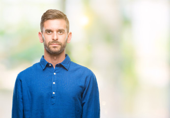 Young handsome man over isolated background with serious expression on face. Simple and natural looking at the camera.