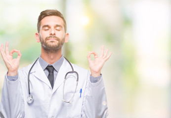 Young handsome doctor man over isolated background relax and smiling with eyes closed doing meditation gesture with fingers. Yoga concept.