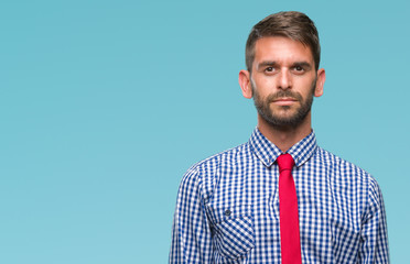 Young handsome business man over isolated background with serious expression on face. Simple and natural looking at the camera.
