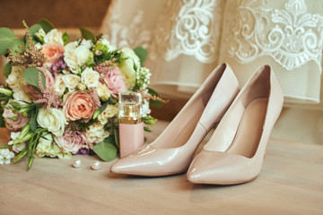 Bride's wedding accessories such as high heel shoes, bouquet, earrings and perfume