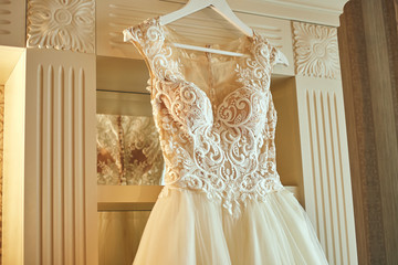 beautiful wedding dress hanging in the room, woman getting ready before  ceremony