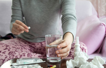 Obraz premium Woman hand with pills medicine tablets and glass of water in her hands. Healthcare, medical supplements concept