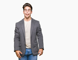 Fototapeta premium Young business man wearing glasses over isolated background making fish face with lips, crazy and comical gesture. Funny expression.