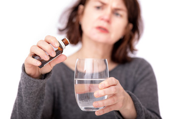 Woman with medicine bottle and water glass