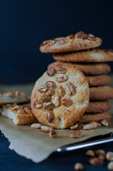 Homemade ruddy cookies with nuts lie pyramid on baking paper on a dark background