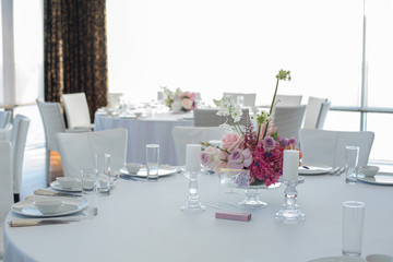 Event white restaurant table served and decorated with delicate fresh flowers