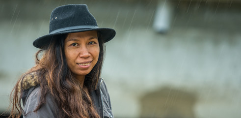Asian woman with black hat and parka standing in the rain smiling © David