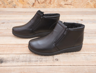 Winter boot with fur lining at wood background, close-up