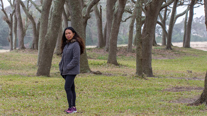 Asian woman with parka standing in front of trees © David