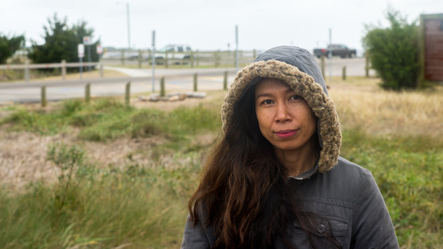 Asian Woman With Parka Standing In Field