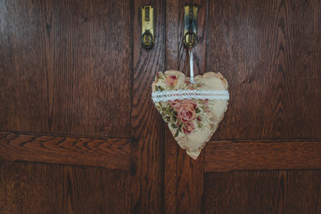 Close-up of an antique wooden closet lock with heart hanger made out of fabric
