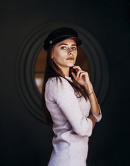 Woman wears stylish kepi on dark background.