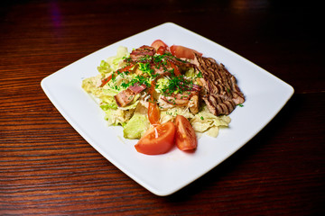 Appetizing dish on a white plate stands on a wooden table, food, snack