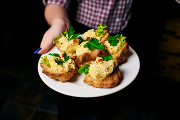 Appetizing dish on a white plate in the hands of the girl waiter, food, snack