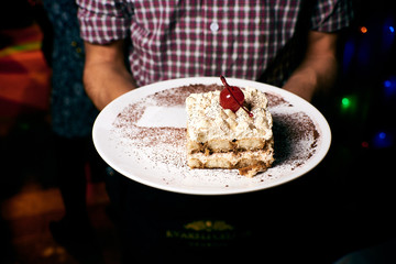 Appetizing dish on a white plate in the hands of the girl waiter, food, snack
