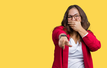 Beautiful plus size young business woman wearing elegant jacket and glasses over isolated background Laughing of you, pointing to the camera with finger hand over mouth, shame expression