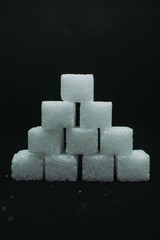 Pile of sugar cubes closeup view on black dark isolated background