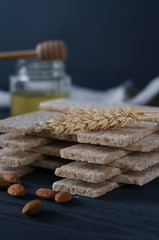 Healthy food. Air dietetic loaves lie on a dark wooden table on a dark background next to the ears of wheat and honey