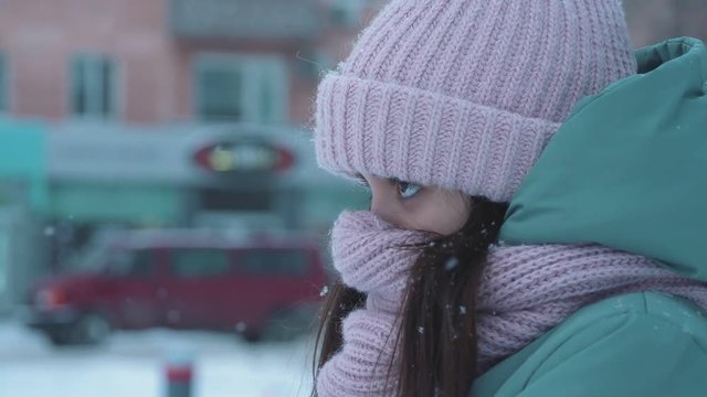 cute frozen unhappy girl standing on the street in snowy day, close up