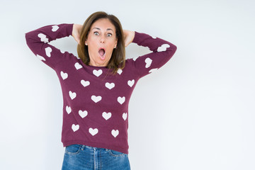 Beautiful middle age woman wearing heart sweater over isolated background Crazy and scared with...
