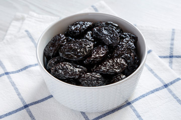 Dry prunes in a bowl, side view. Close-up.