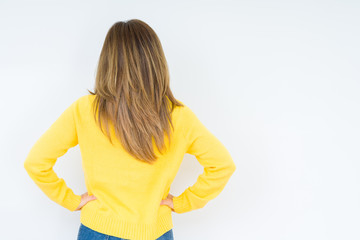 Beautiful middle age woman wearing yellow sweater over isolated background standing backwards looking away with arms on body