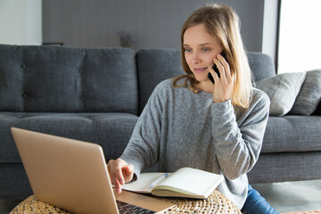 Positive successful businesswoman enjoying work on weekend. Young woman in casual using laptop and...