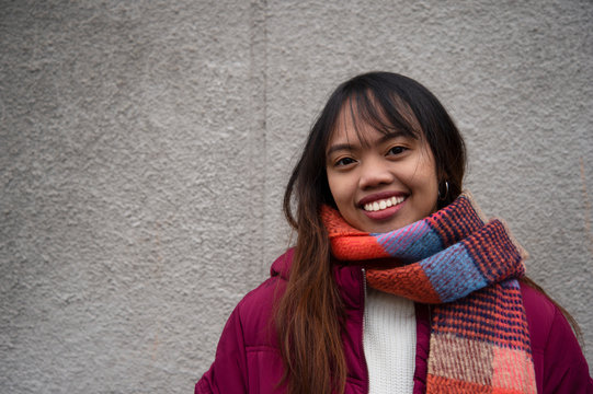 smile Filipino young teen woman Asian portrait with red coat and scarf with grey wall background