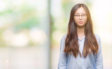 Young asian business woman wearing glasses over isolated background with serious expression on face. Simple and natural looking at the camera.