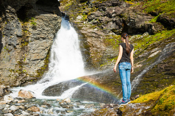 Young woman next to Waterfall in the Geiranger valley near Dalsnibba mountain, Norway