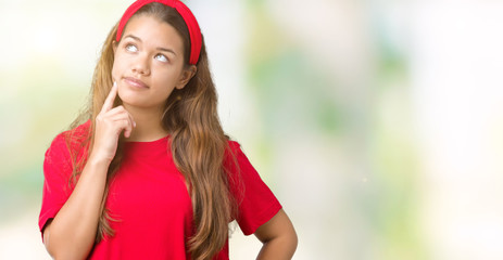 Young beautiful brunette woman wearing red t-shirt over isolated background with hand on chin thinking about question, pensive expression. Smiling with thoughtful face. Doubt concept.